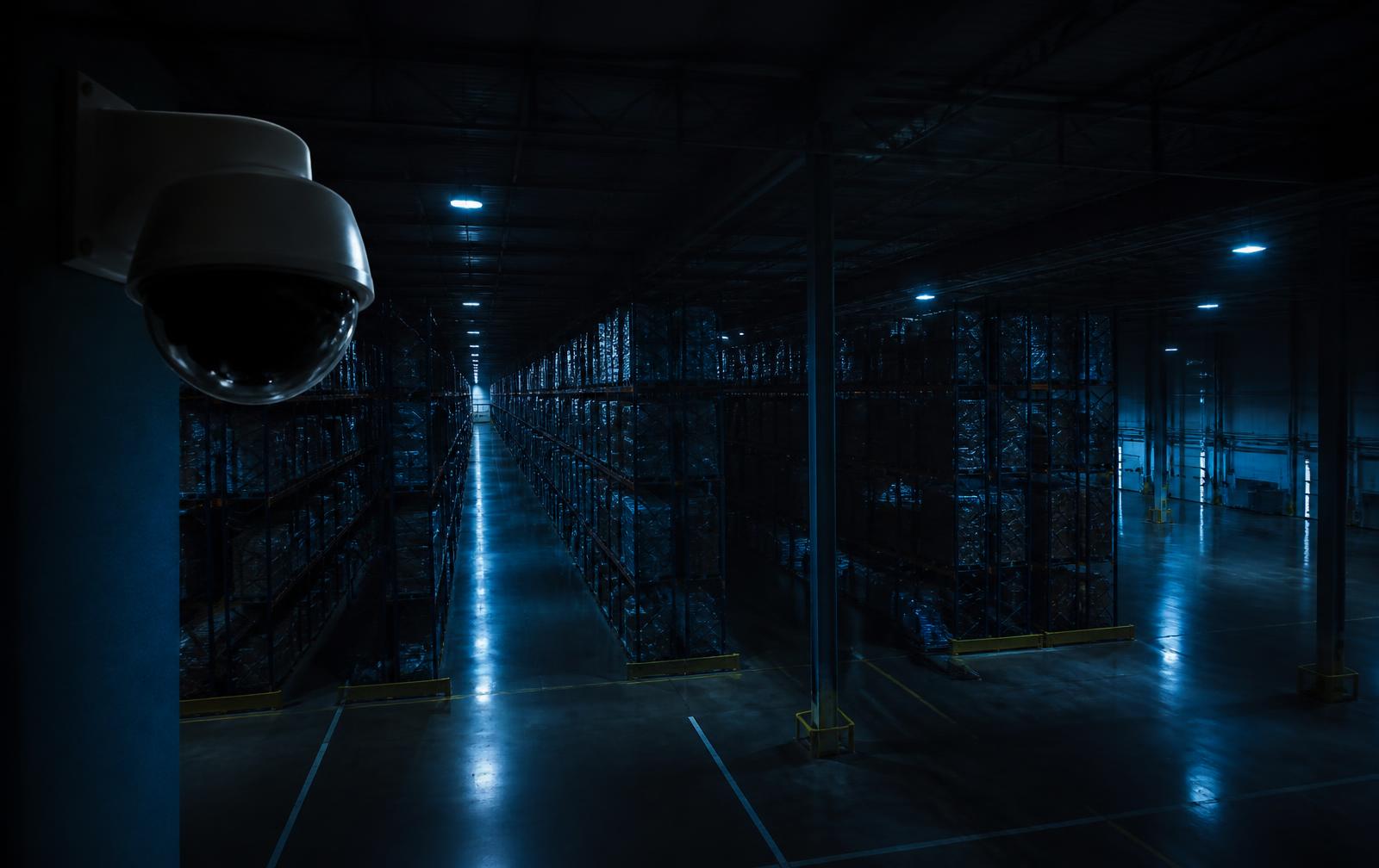 Interior of a large modern warehouse with racking aisles monitored by security cameras